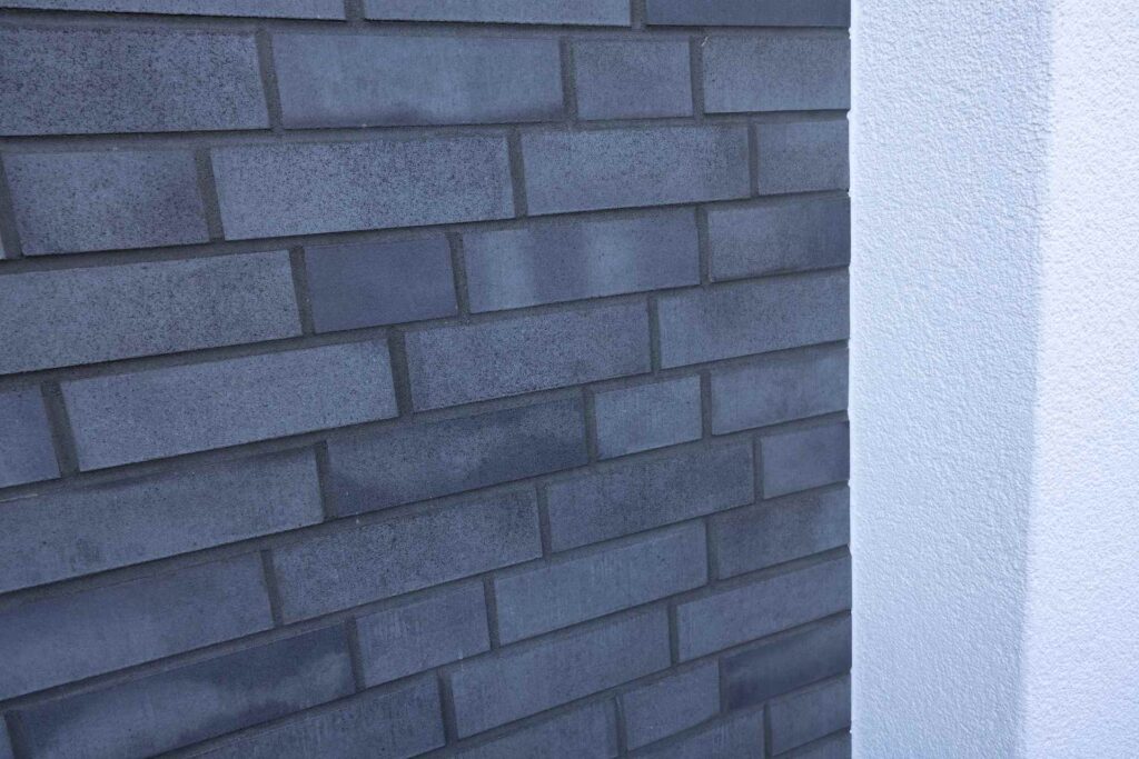 Moderne Klinkerriemchenfassade in Blaugrau neben weißer WDVS-Fassade an einem Wohngebäude