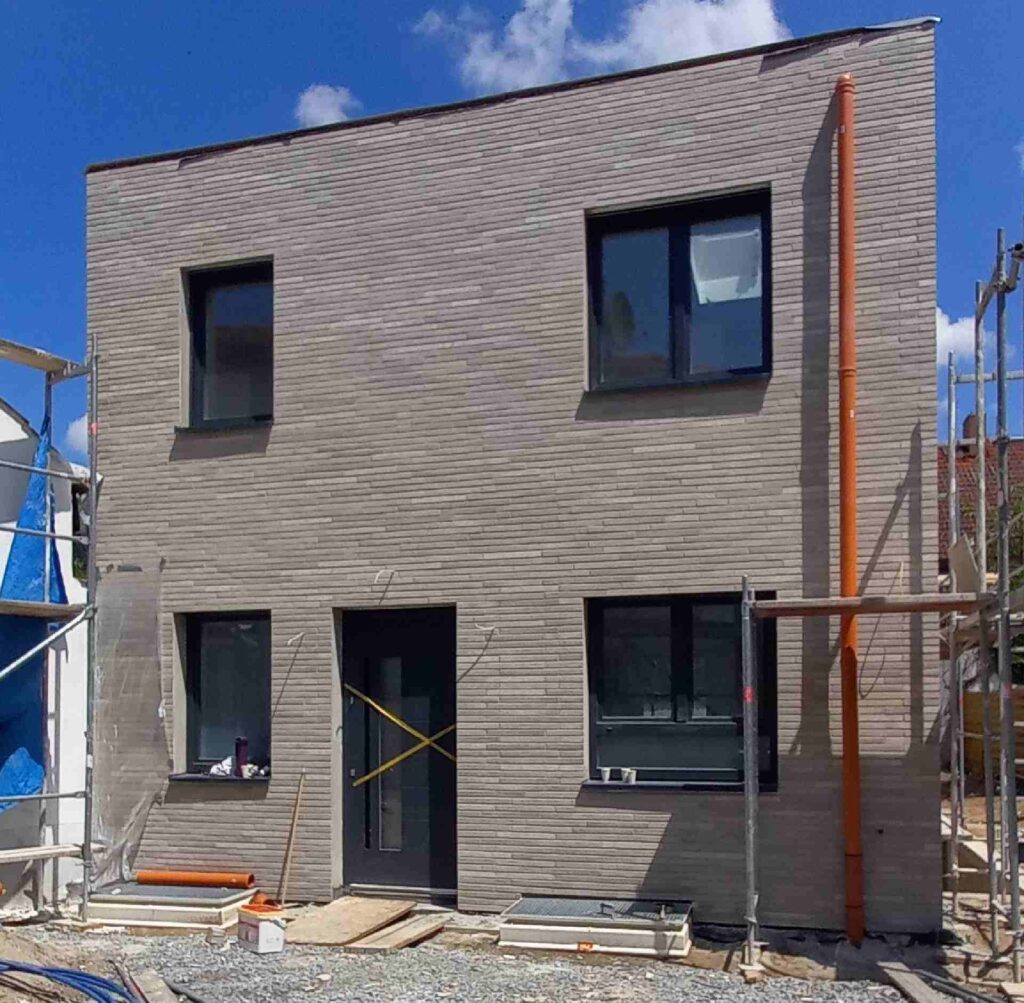 Neubau mit moderner Klinkerriemchenfassade in grauer Optik, große Fenster und Fassadendämmung im Rohbauzustand