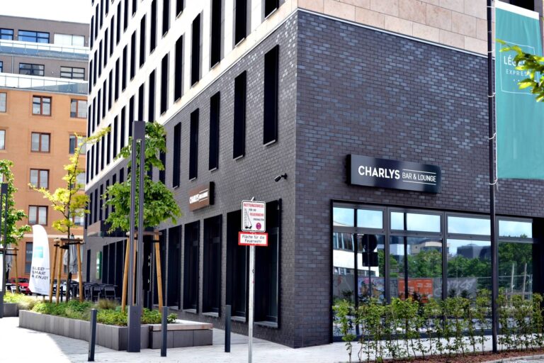 Moderne Klinkerriemchenfassade eines Geschäftsgebäudes mit Bar Charlys und großen Fenstern in urbaner Umgebung