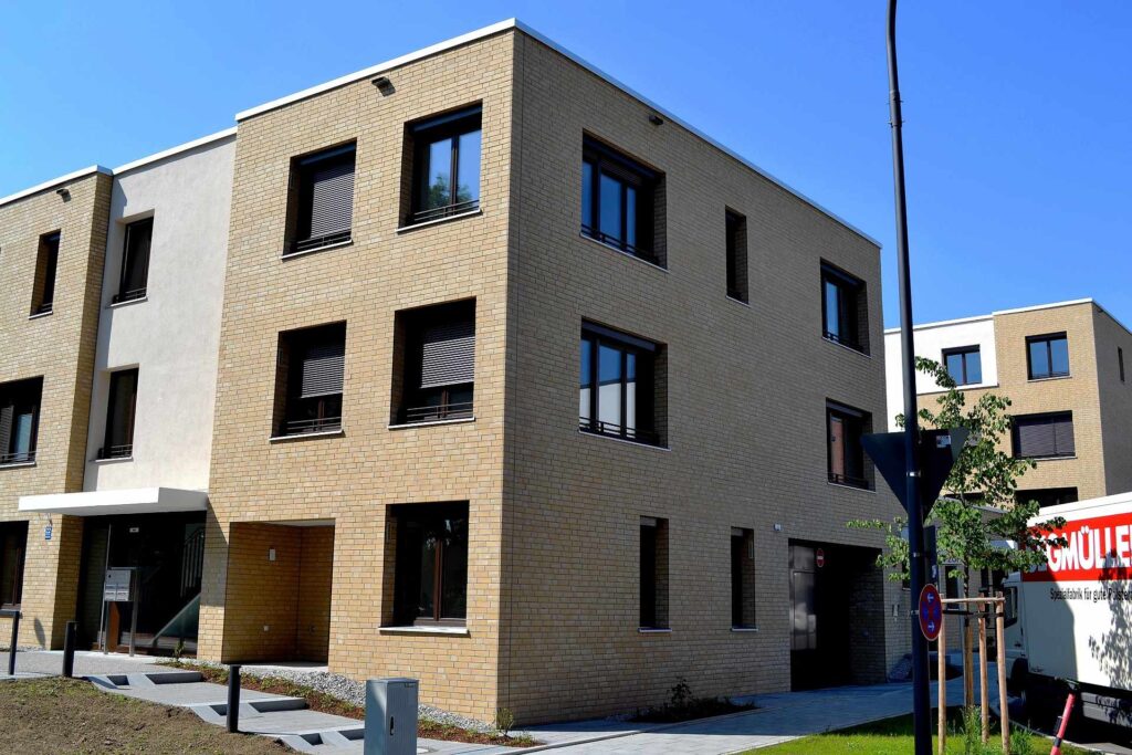 Moderní řadový dům s klinkerovou páskovou fasádou a bílými detaily pod modrým nebem