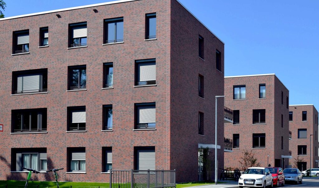 Moderní bytové domy s klinkerovou páskovou fasádou v červenohnědých odstínech s černými okenními rámy