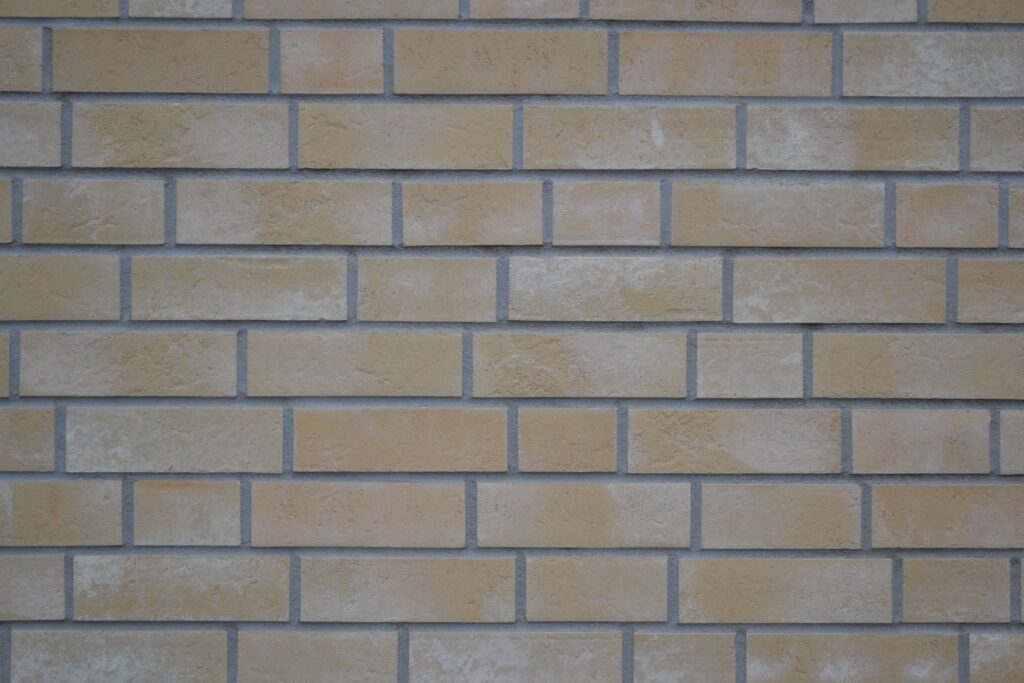 Fasáda z klinkerových pásků v béžové barvě se šedou spárou, moderní cihlová pásková fasáda domu