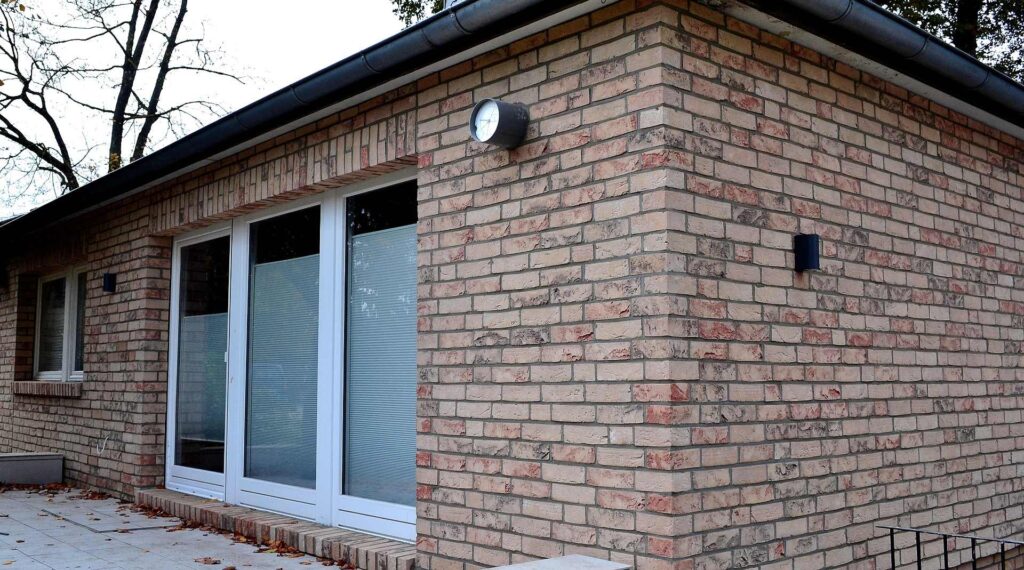 Moderní dům s klinkerovou páskovou fasádou v béžovo-červených tónech a bílými plastovými okny