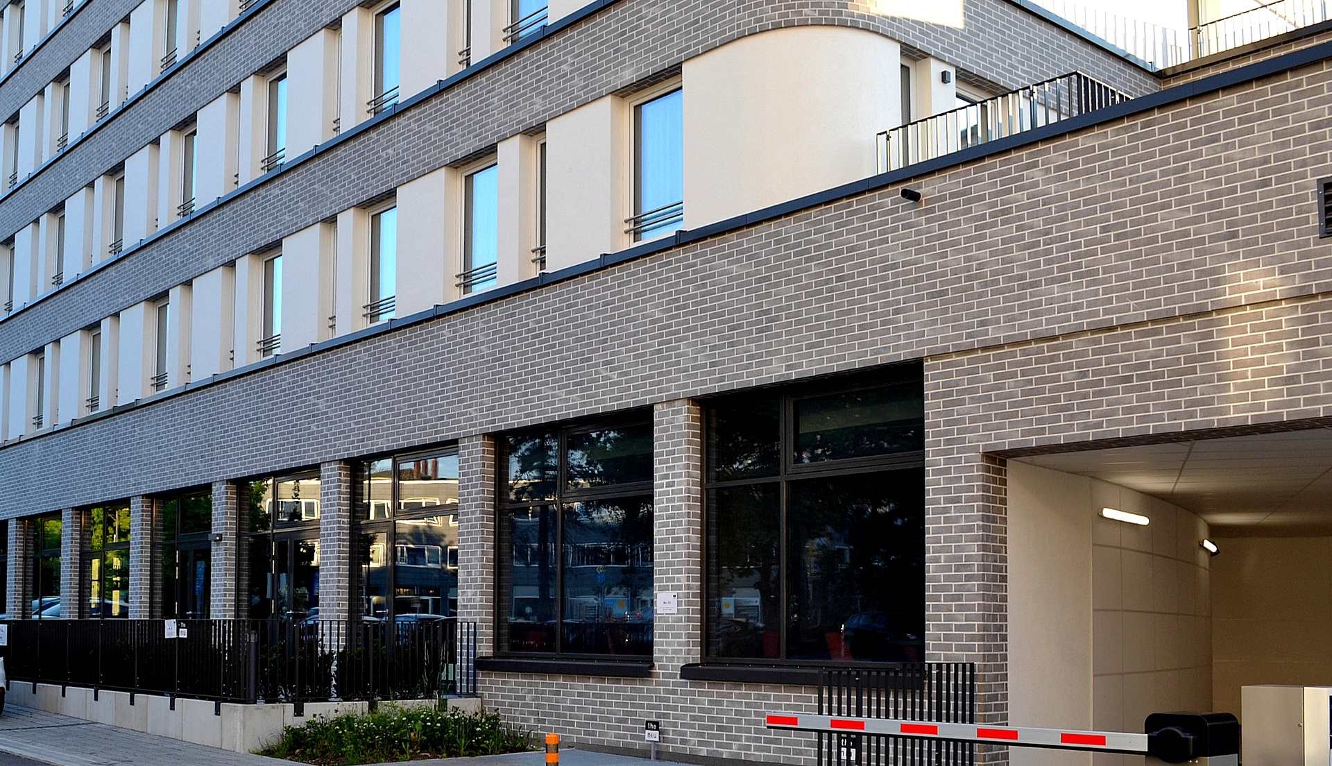 Moderní bytový dům s klinkerovou páskovou fasádou a velkými okny v přízemí s komerčními prostory