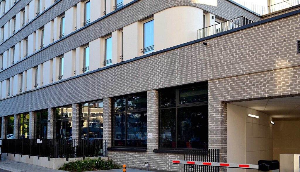 Moderní bytový dům s klinkerovou páskovou fasádou a velkými okny v přízemí s komerčními prostory