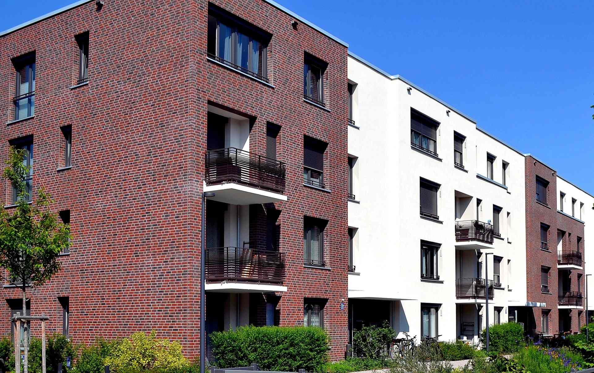 Moderní bytový dům s fasádou z klinkerových pásků a bílou omítkou, balkony s kovovým zábradlím