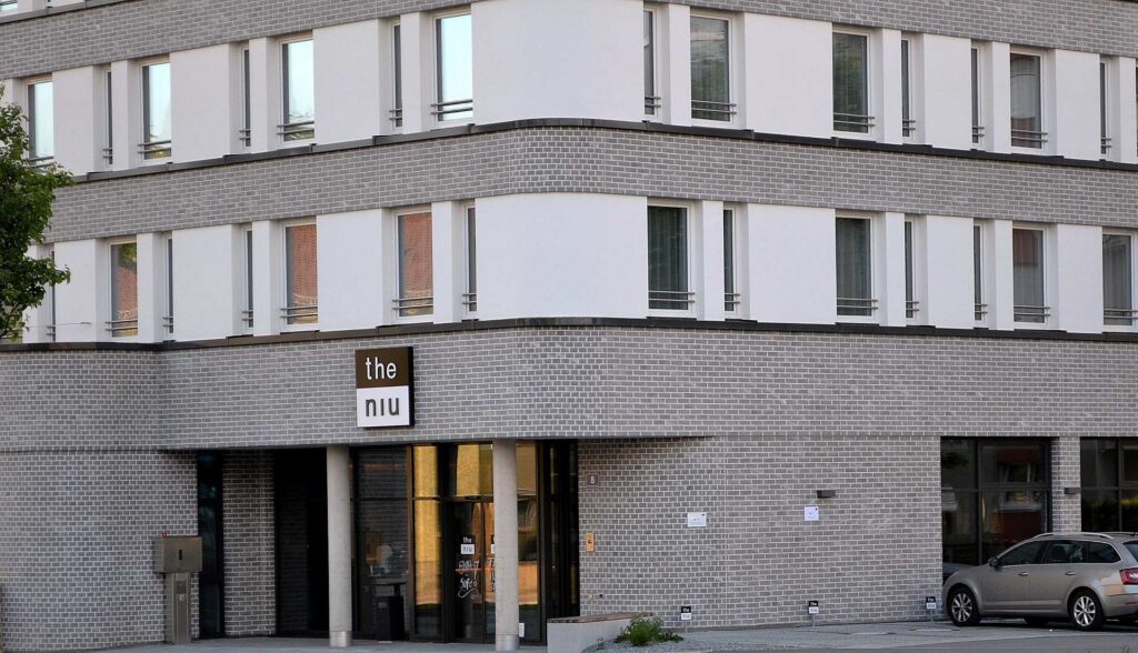 Moderní bytový dům s klinkerovou páskovou fasádou a bílými prvky, hotel the niu v přízemí