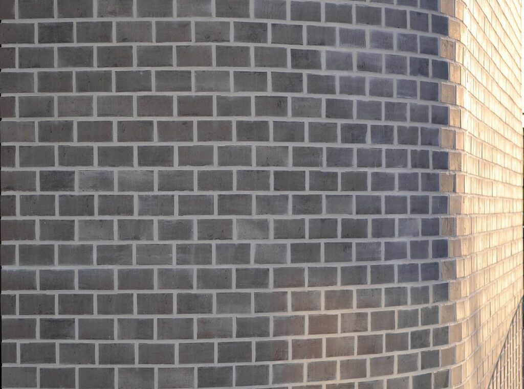 Klinkerová pásková fasáda s tmavými obkladovými pásky na rohu budovy s přechodem barev