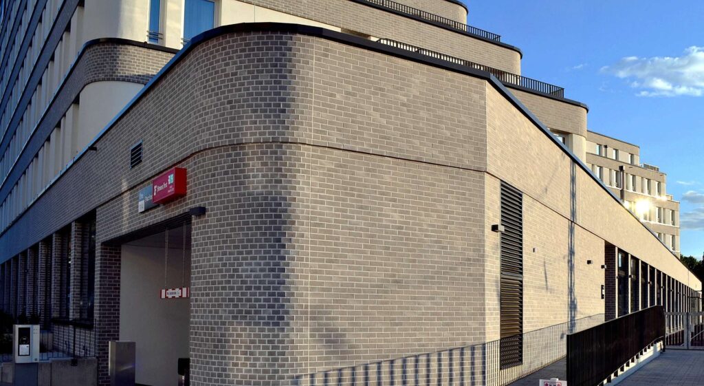 Moderní budova s klinkerovou páskovou fasádou v béžových tónech a zakřivenými liniemi architektury