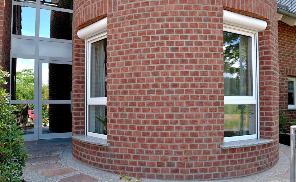 Moderní dům s klinkerovou páskovou fasádou a bílými plastovými okny s parapety z přírodního kamene