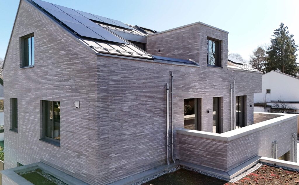 Moderní dům s klinkerovou páskovou fasádou a solárními panely na střeše