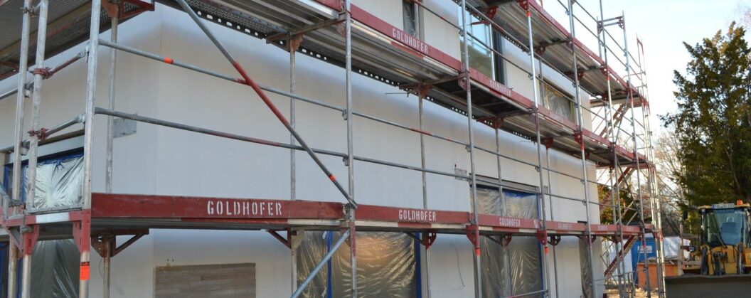 Zateplení fasády rodinného domu s lešením během rekonstrukce, příprava pro novou fasádu z klinkerových pásků