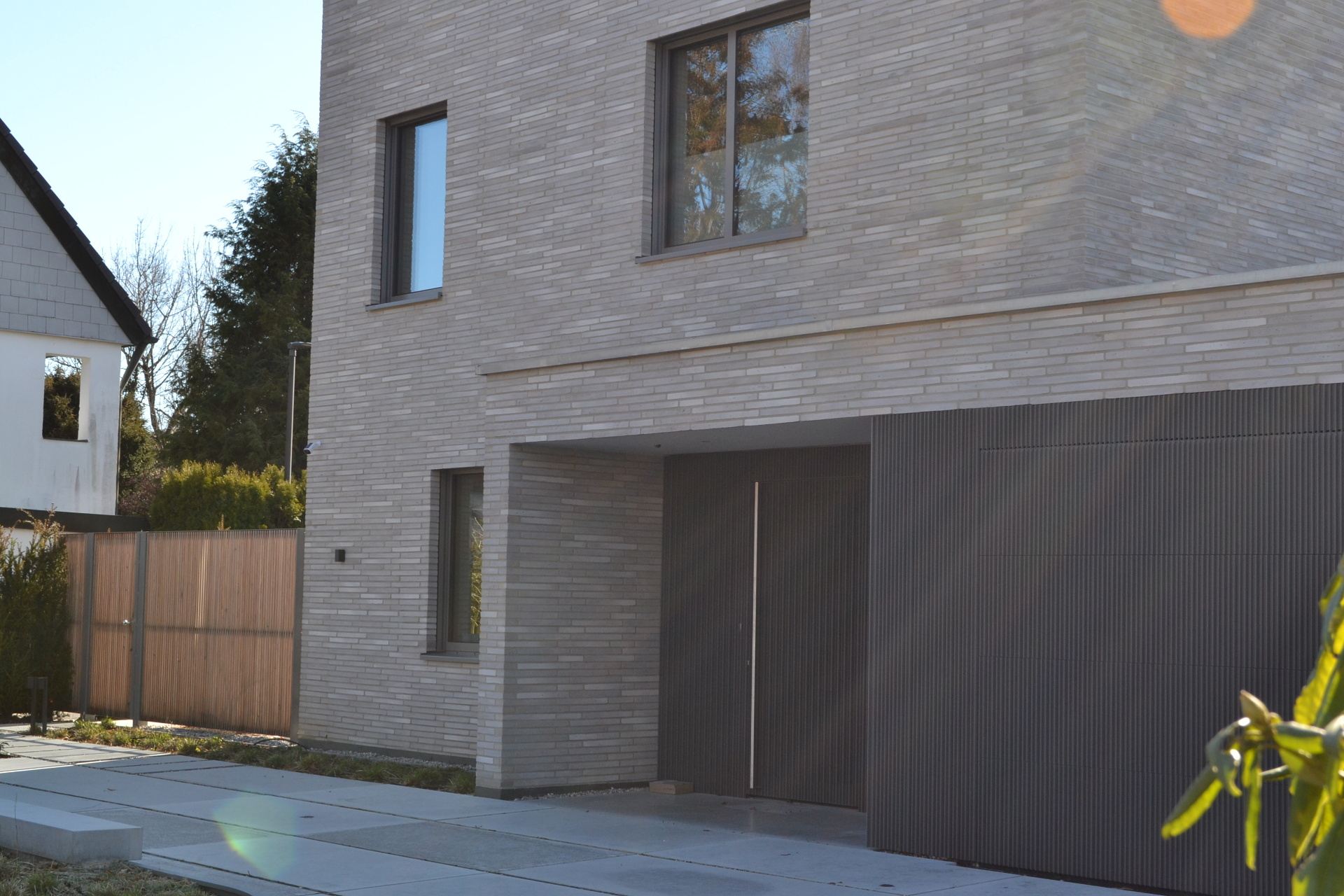 Moderní dům s fasádou z klinkerových pásků a integrovanou garáží s tmavým obkladem