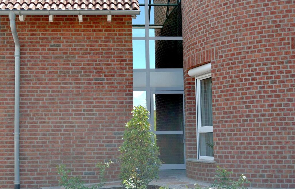 Moderní cihlová pásková fasáda rodinného domu s velkými okny a vstupním portálem