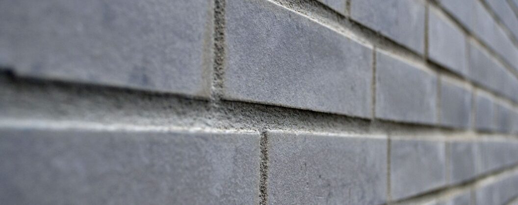 Nahaufnahme einer grauen Klinkerfassade mit schmalen Klinkerriemchen und sichtbaren Fugen in Perspektive
